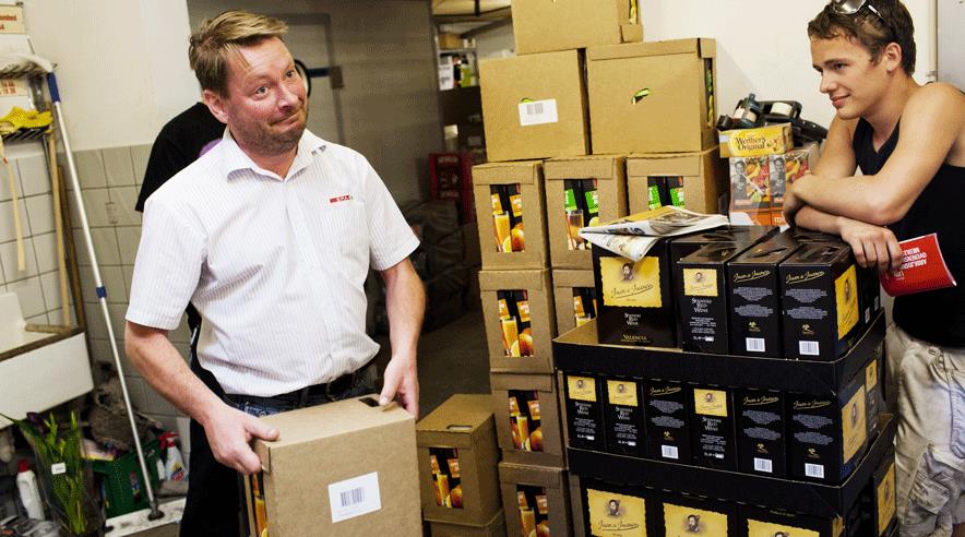 Søren Hagelund viser jobpatruljen en kasse med juice, der vejer over de tilladte 12 kilo, mens fritidsjobber Patrick Weische på 15 kigger på. (Foto: Uffe Weng)