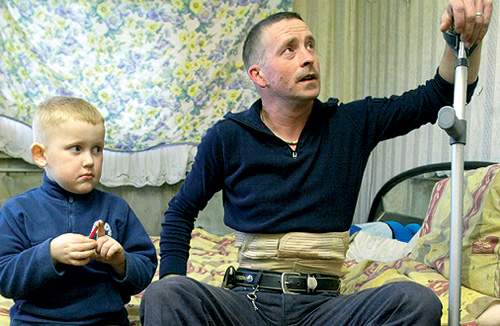 Dean Tolhurst sidder på fjerde måned med en brækket ryg på sit sygeleje og uden en krone på lommen. Her sammen med sønnen Mantvydus.