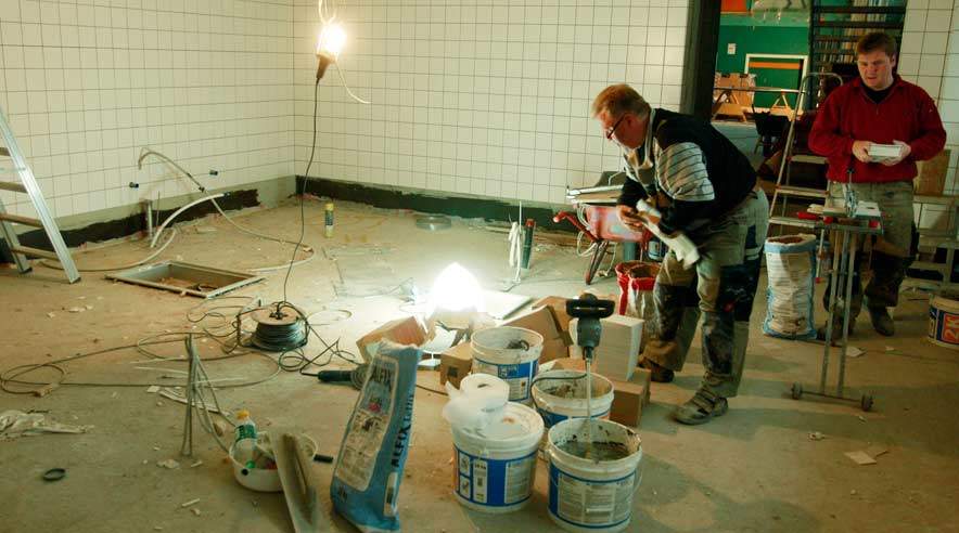 De to tyske murere, far og søn, i gang med flisearbejdet i badeværelse på Amager Fælled Skole. Det er deres entreprise, der giver anledning til, at kommunen beskyldes for social dumping.  (Foto: Harry Nielsen.)