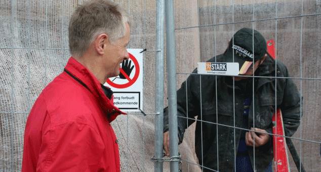 Fagbevægelsens kontakt med de omkring 15 polske arbejdere er begrænset. Her er det faglig sekretær John Andersen, TIB Nordjylland, der gennem hegnet kommunikerer med en af polakkerne. (Foto: privat.)