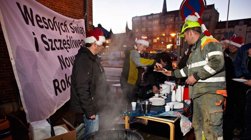 På havnen i Aarhus har firmaet Budmoex overenskomst. Men de polske betonarbejdere tjener 50 kroner mindre i timen end deres danske kollegaer på de andre pladser. Her får de æbleskriver og glögg og en snak om 3F kort før jul. (Foto: Henrik Bjerregrav)
